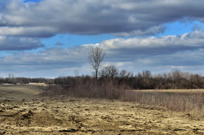 a barren field and a road under clouds