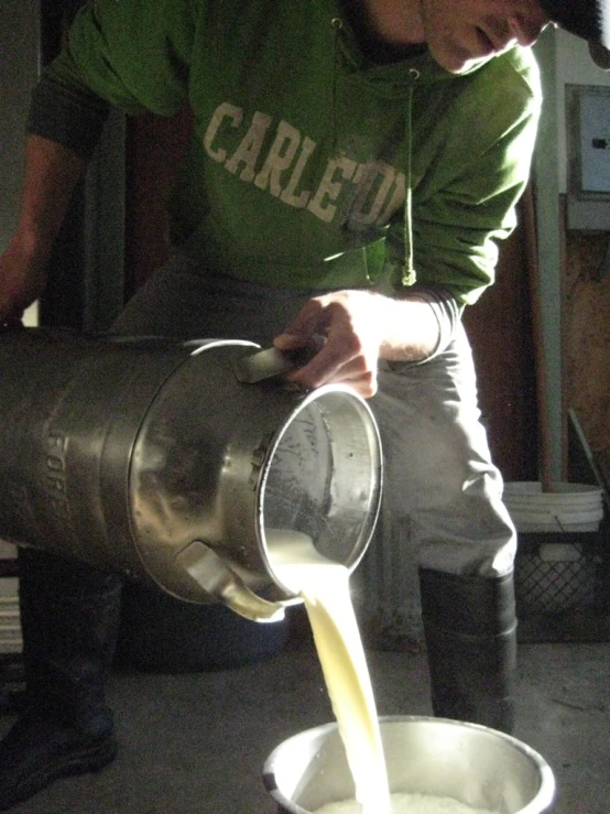 a young man pouring a glass of milk into a cup