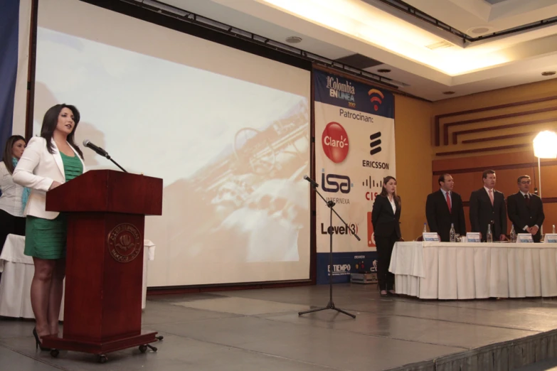 three people standing at podium while speaking in front of a crowd