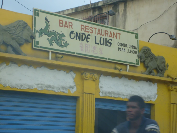 a man walking down a street near a sign for the bar restaurant conde lus