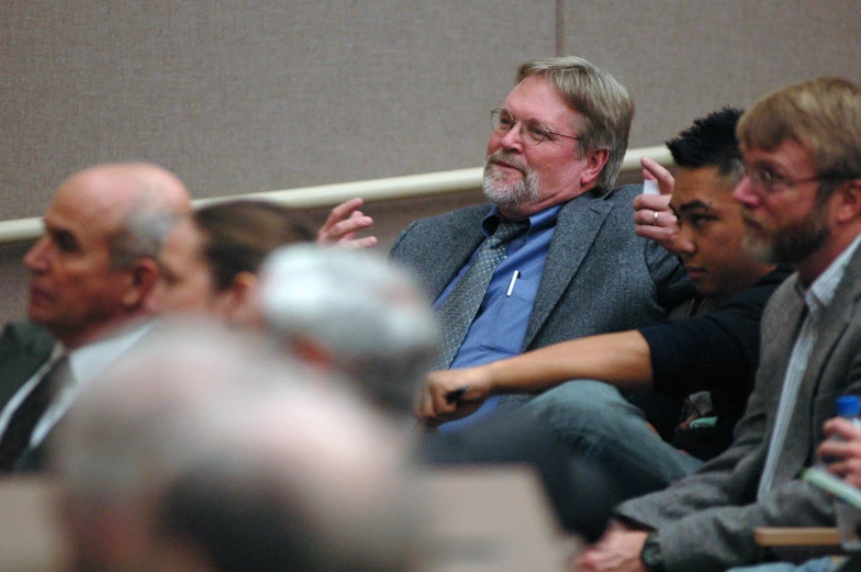 a man is sitting in a conference room with his hands up