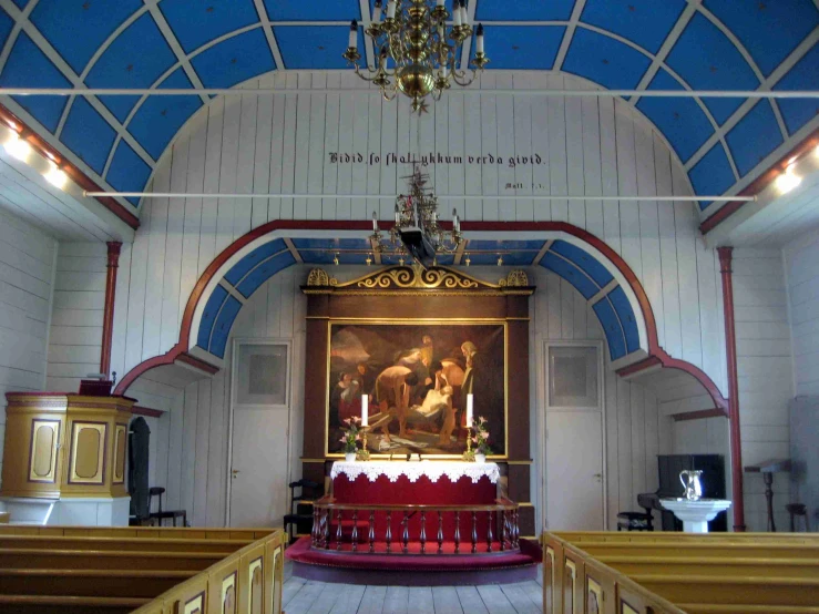 an interior view of a church with wood benches and red and white cloth on the ceiling