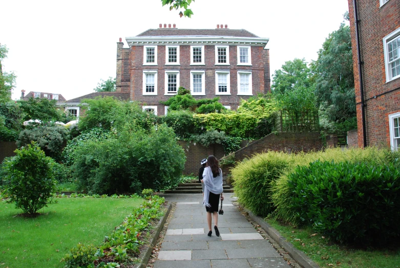 a woman that is standing in the grass by some bushes