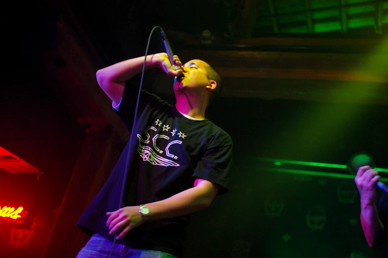a man sings into a microphone in front of a green light