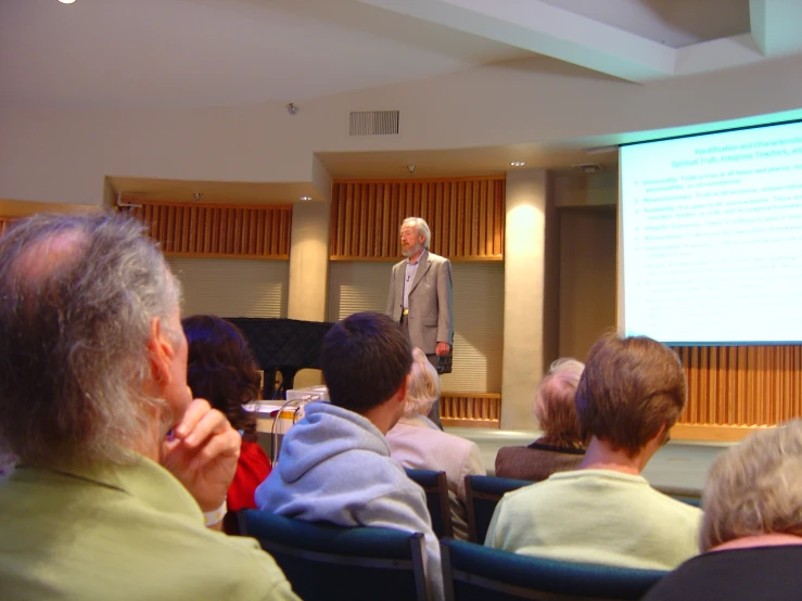 man talking to audience during presentation on large screen