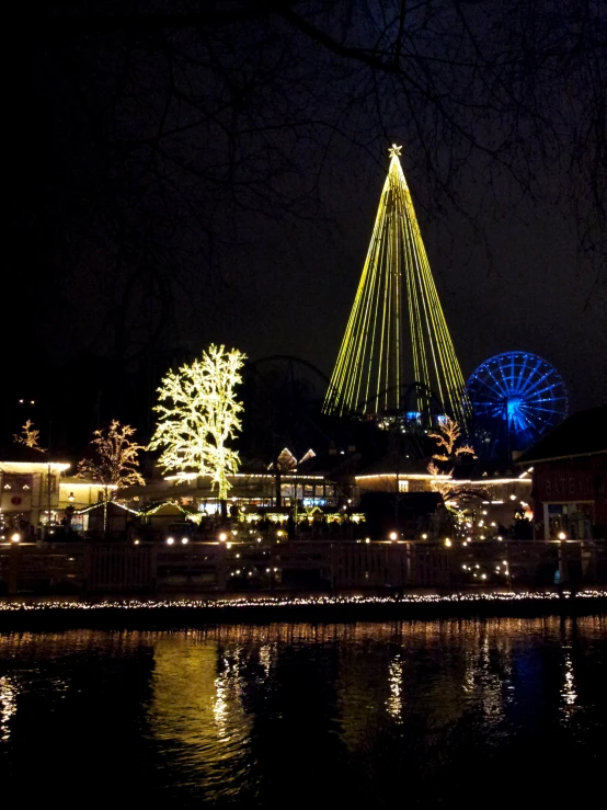 a large christmas tree in the dark by the water