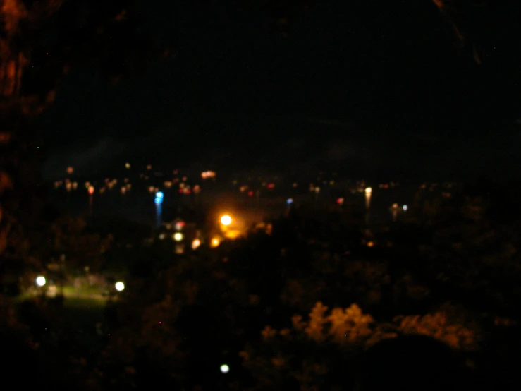 an outdoor view at night of a city from a hill