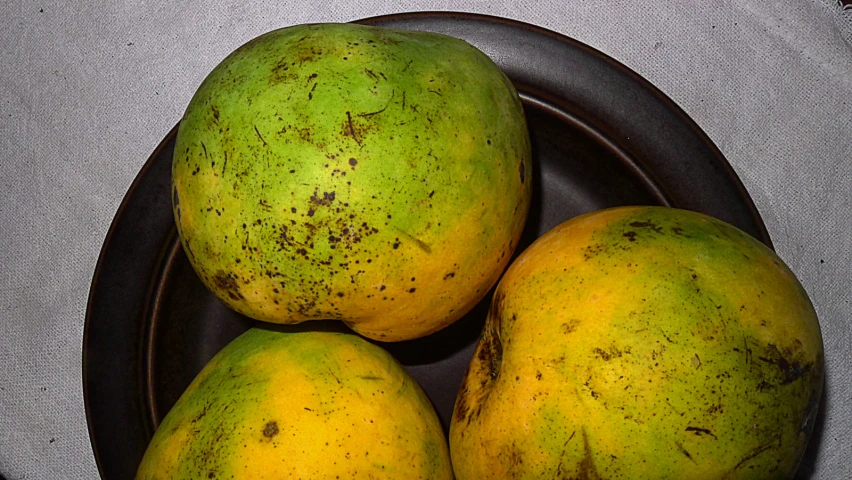 three mangoes in a bowl with one on top and four inside