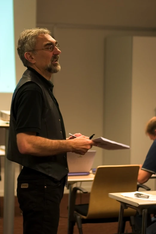 the man is holding papers standing behind a microphone