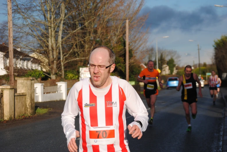 man in an orange and white striped vest running a race