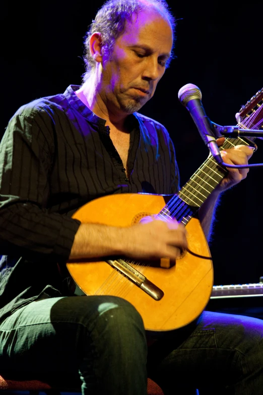 a man that is sitting down playing a guitar