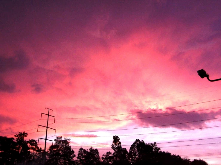 a street light sitting below an orange and purple sky