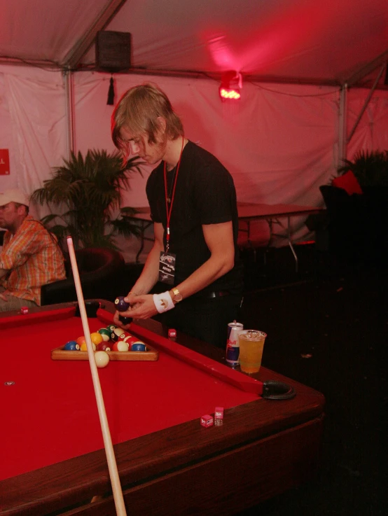 two men playing pool in a tent at a gathering