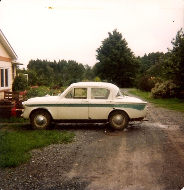 an old fashioned car sitting on a gravel road