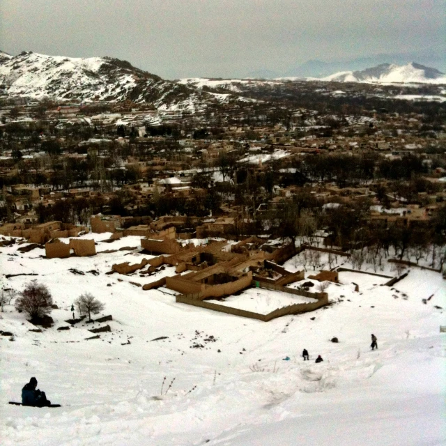 some skiers snow buildings and mountains with trees