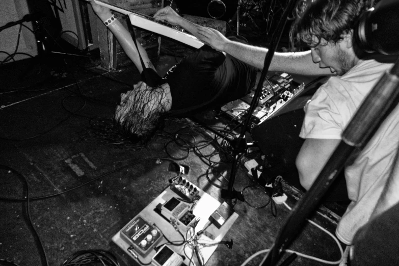 two men playing guitar with headphones and recording equipment