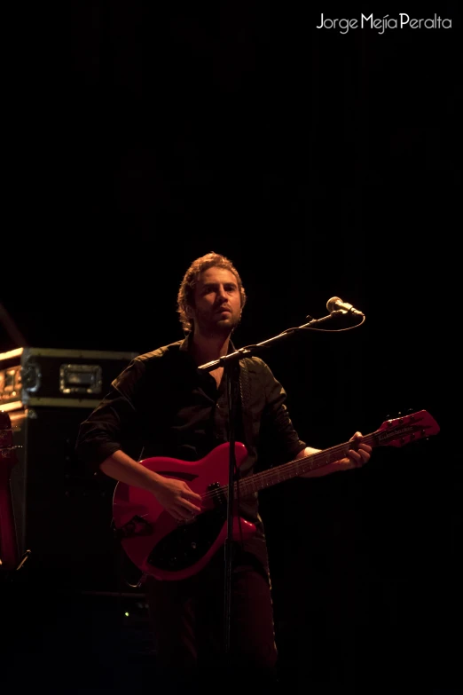 a man is playing guitar in the dark