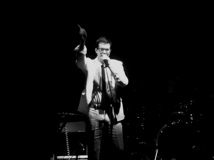 a man wearing glasses and a tie standing on stage