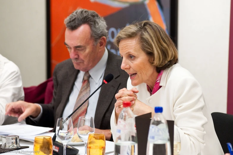 three people seated in a room during a conference