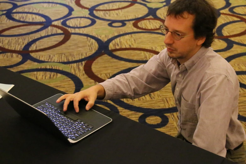 a man in glasses works on a laptop computer