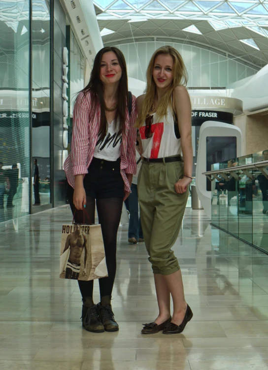 two women standing side by side on a floor in front of a building