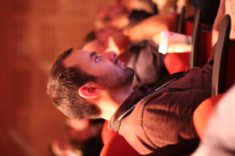 a man looks down while sitting in a group of people