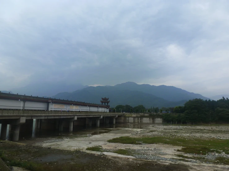 a bridge in the middle of a river with mountains in the background