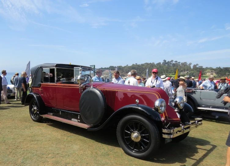 an old fashion car on display in front of other people