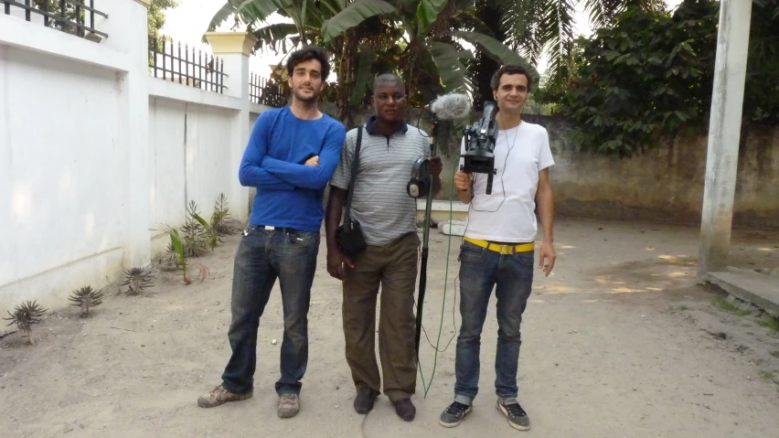 three guys pose for a po while holding cameras