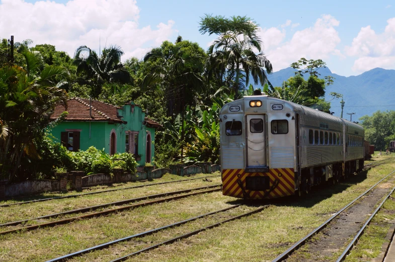 silver train traveling down train tracks in the rural area