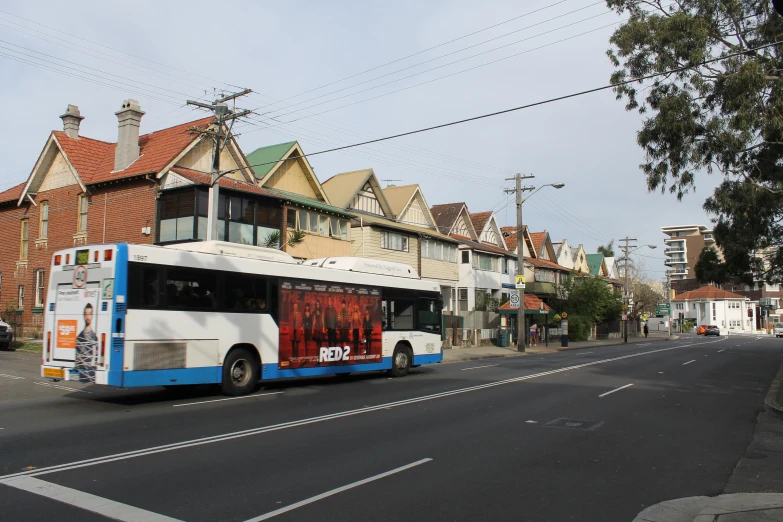 a bus driving down a street past a row of buildings