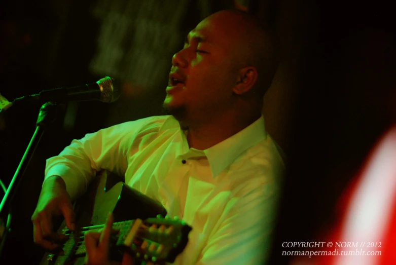 a man with a microphone singing and playing a guitar