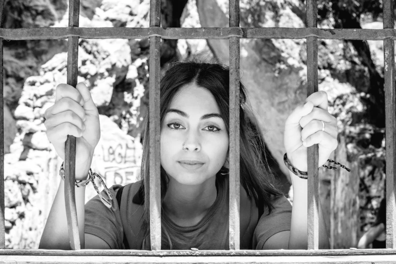 a woman standing in a fenced area with her hand on bars