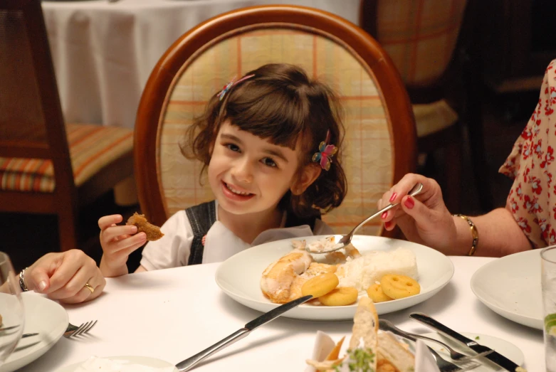 a little girl sitting at a table eating