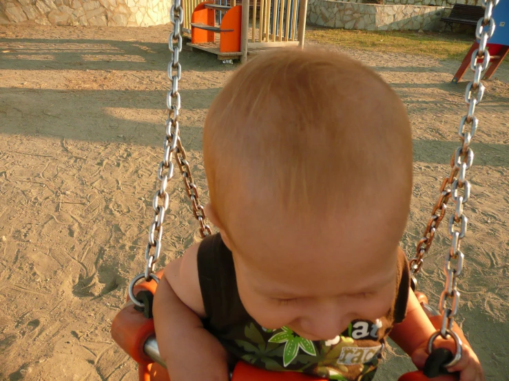 the baby is playing in his swing at the park