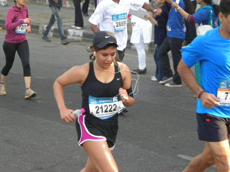 a woman is running with other runners on a busy street