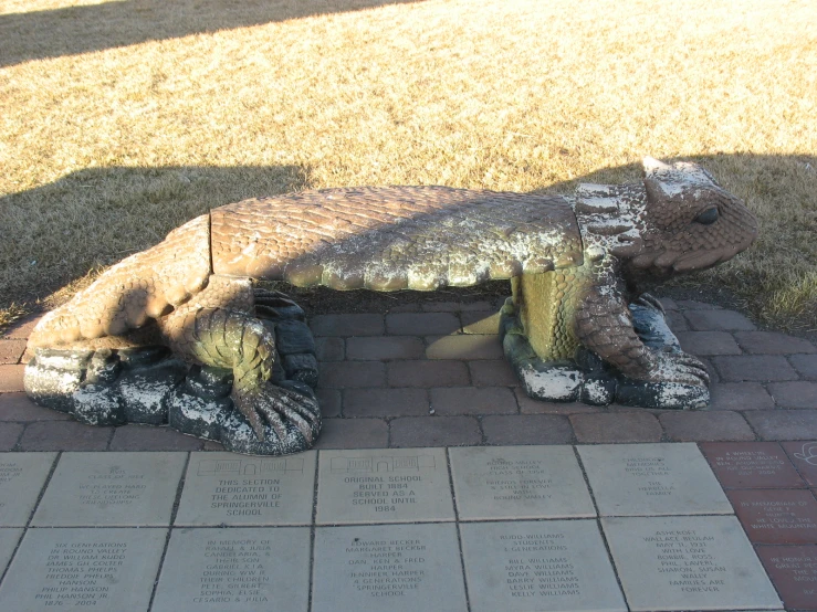 a large dinosaur statue on a brick sidewalk