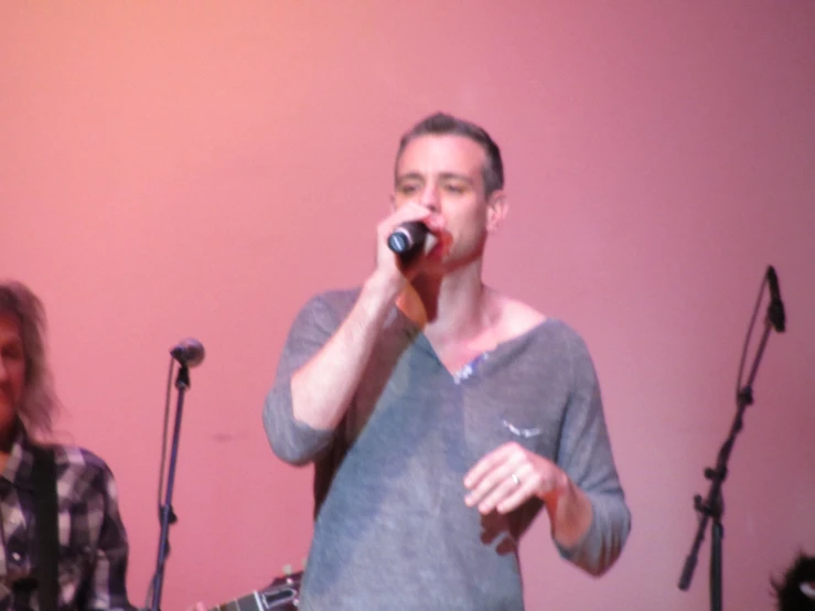 a man standing next to another man while holding a microphone