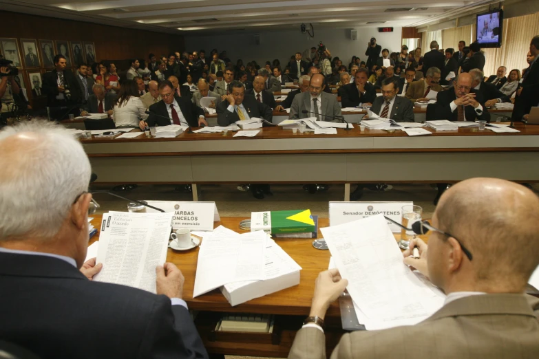 a group of people are sitting at a table with papers and pen in front of them