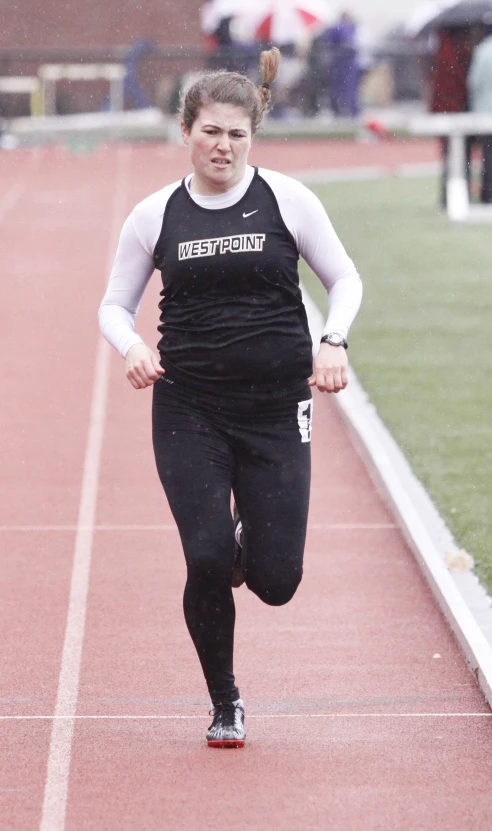 a woman is running on the track wearing black pants