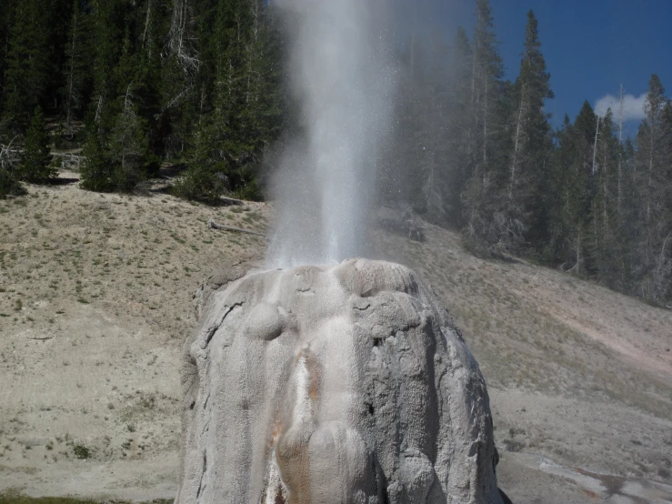 a large geyser is spewing out water onto a mountain slope