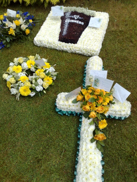 a large floral cross sits among flowers in the grass