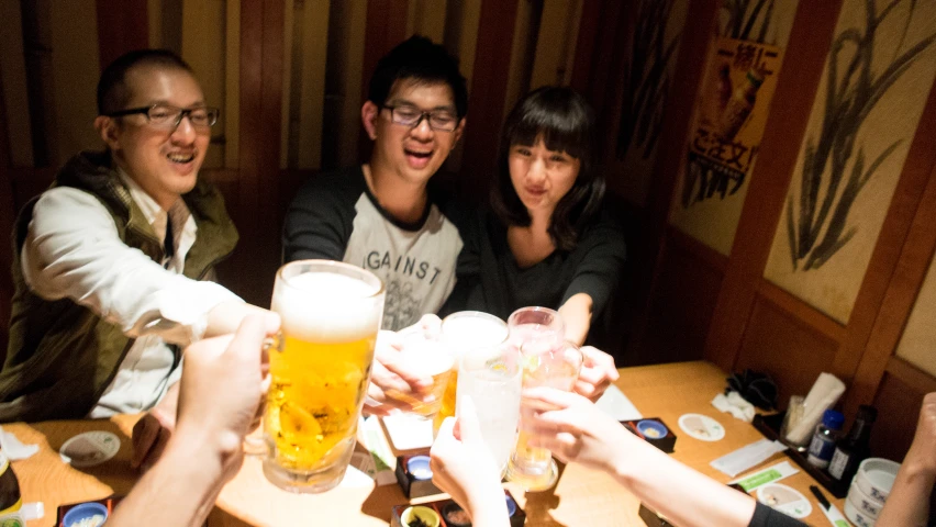 five people toast at a table with beers in the foreground