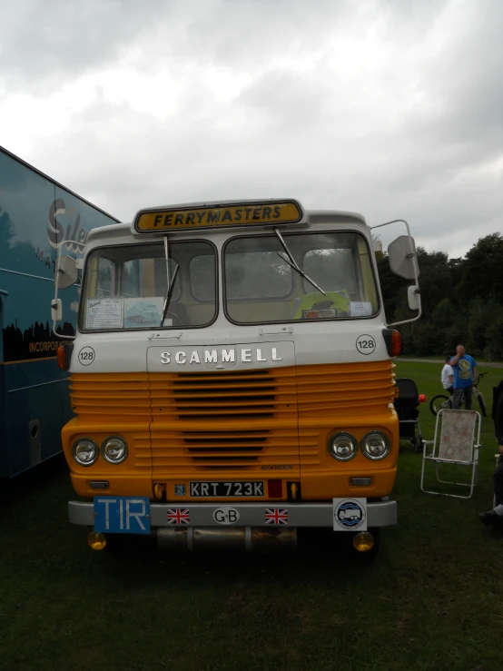 an orange and white bus parked on top of a field