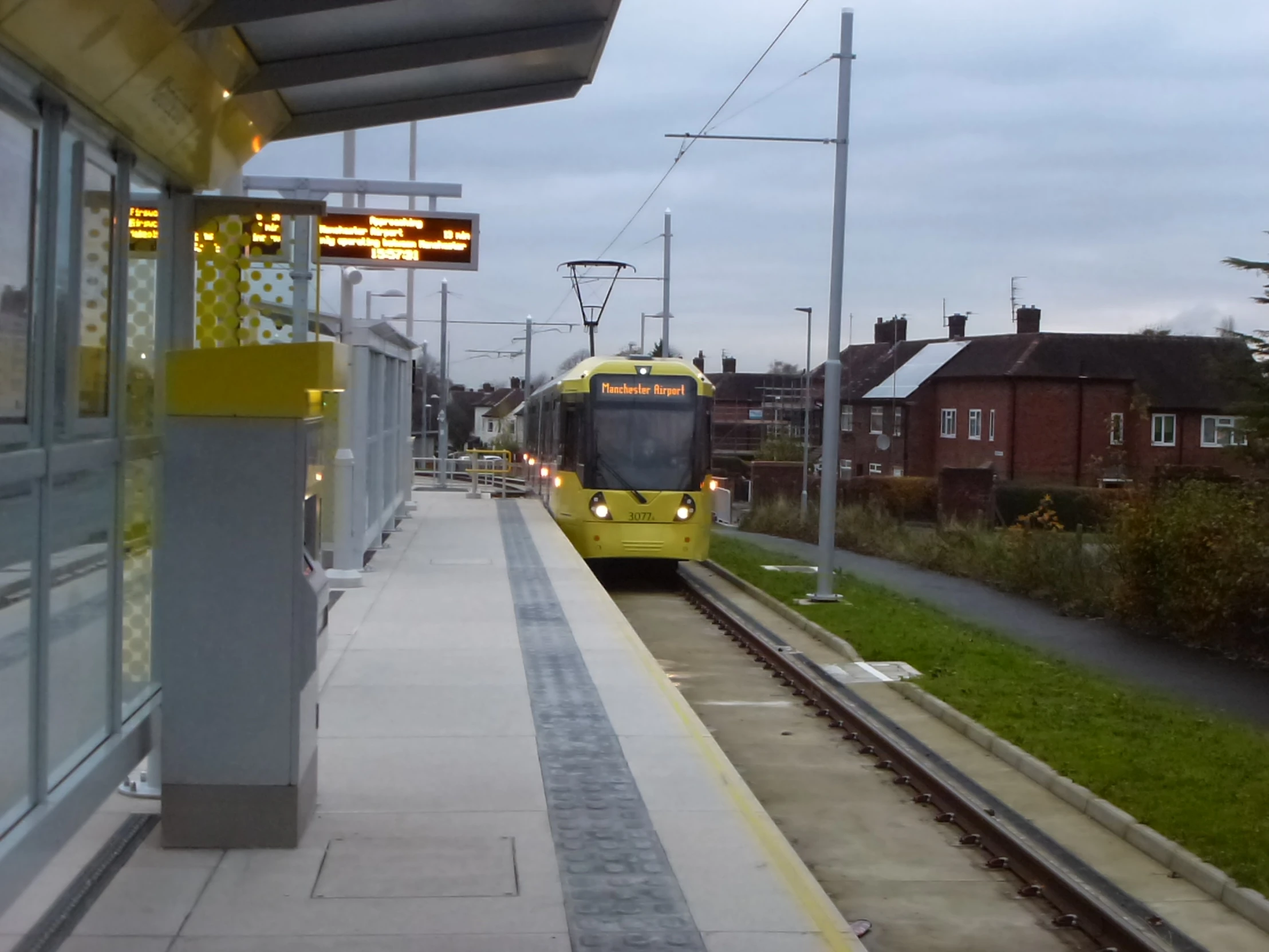 a green train sits next to a train stop