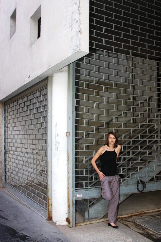 a woman leaning against the side of a building with brick walls