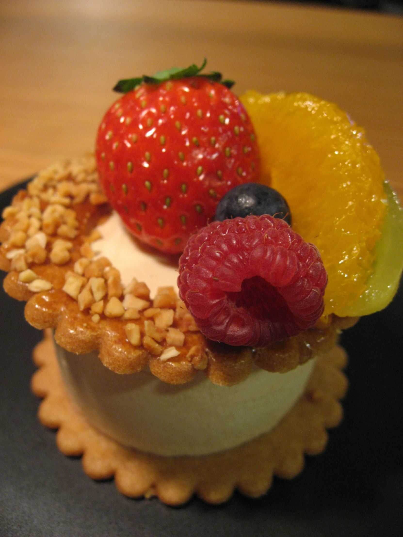 closeup of fruit topped cake on black plate