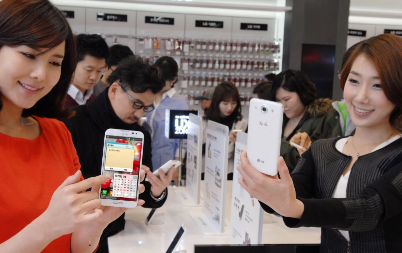 two women are holding up cellphones at a store