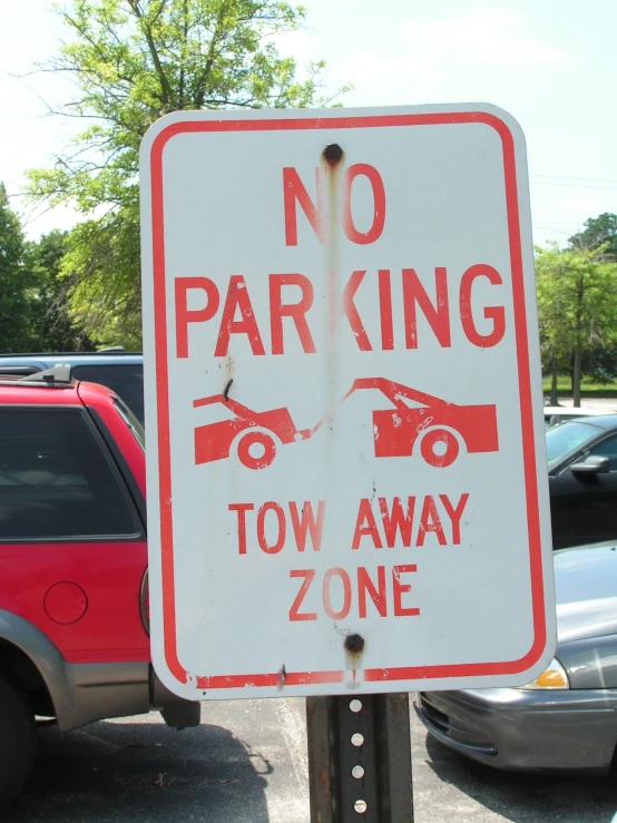 a no parking sign in a lot with cars around it