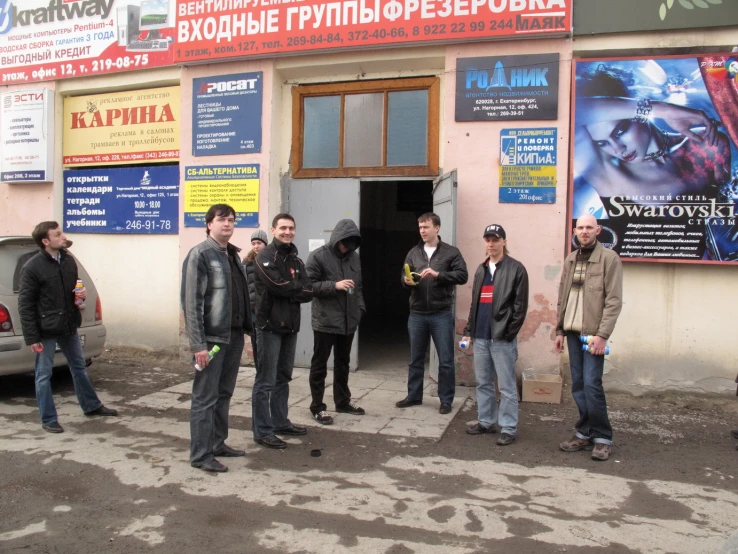 several men standing in front of a shop talking